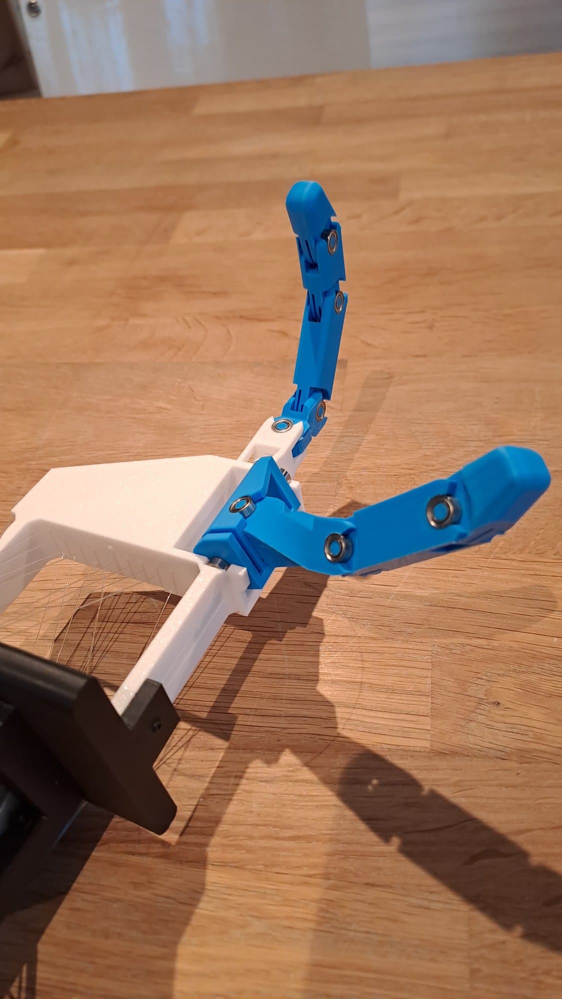 The blue index finger and thumb of the prototype seen from a three-quarter angle.