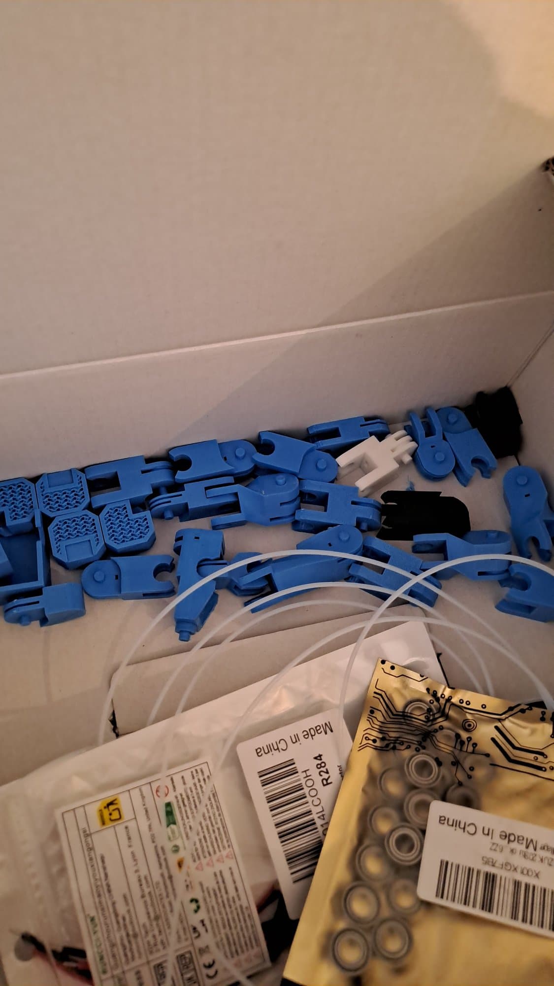 A box of blue 3D-printed finger segments, white tubing and bags of small bearings.